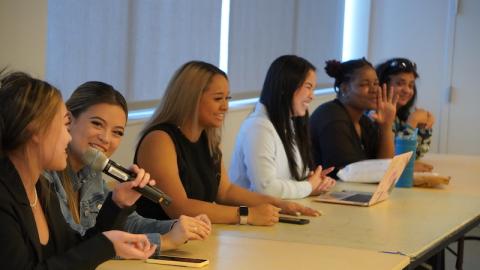 A group of students gathered at a table speaking.