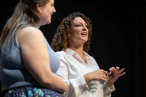 Two women stand on stage and sing