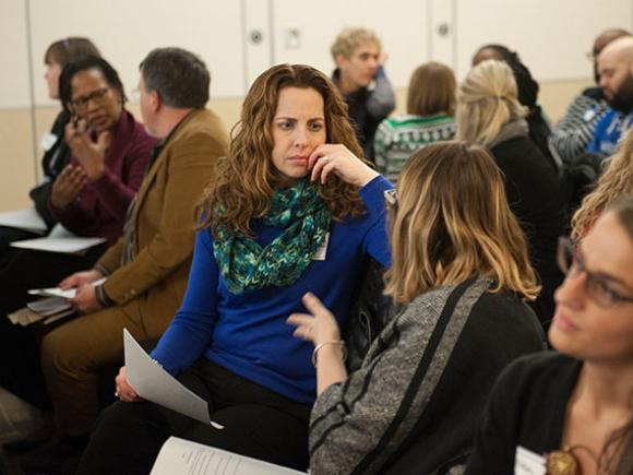 A small classroom of diverse students engage in discussions.