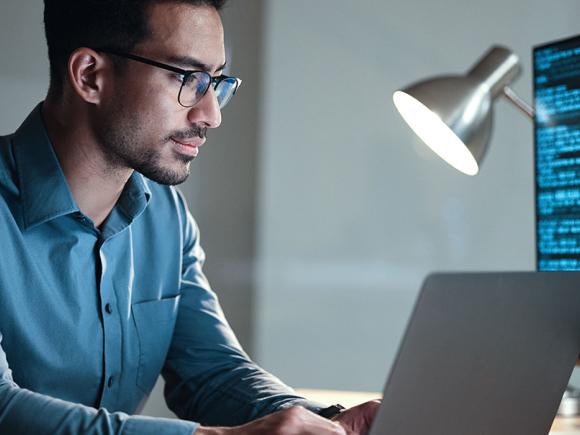 Cyber Security guy sitting on laptop with lamp