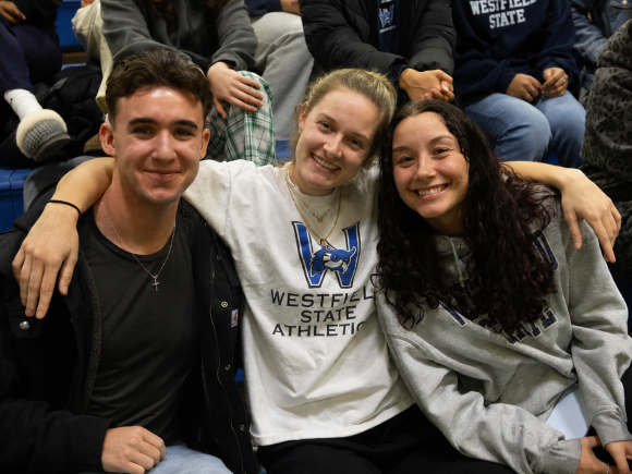 Three students smiling together at a pep rally.