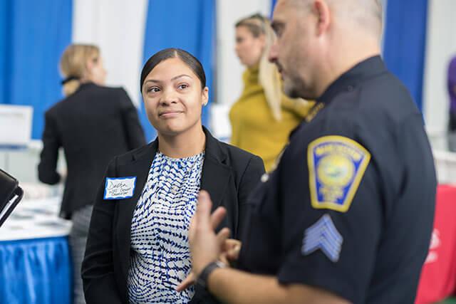 A student engaging in conversation with a police officer at an event.