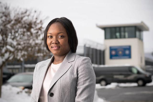 A student wearing a suit stands in front of a correctional facility.