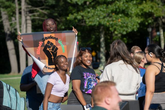 Members of the Black Student Union smiling at the club fair on the campus green.