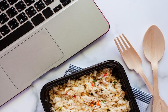 a laptop computer open with a lunch container