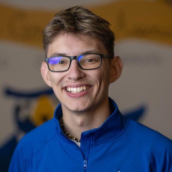 SGA VP of Community Engagement and Outreach, Tyler wearing a blue shirt smiling.