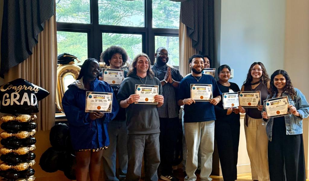 Students smiling holding diplomas.